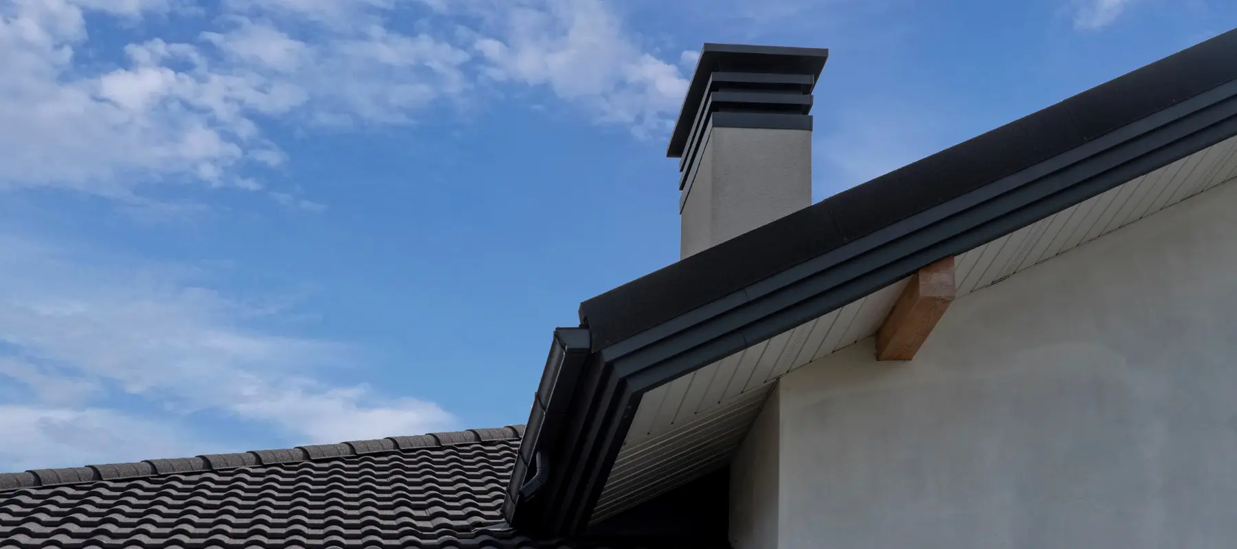 chimney on gable roof with metal tile and vented soffit